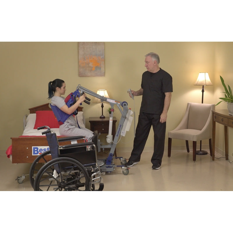 Bestcare SA400 ProCare sit-to-stand lift with person in sling lowering to the bed in new condition